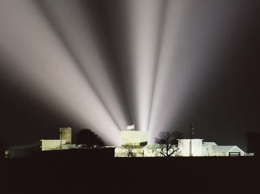 Spotlights directed at the Branch Davidian residence slice through the night sky on April 15, 1993